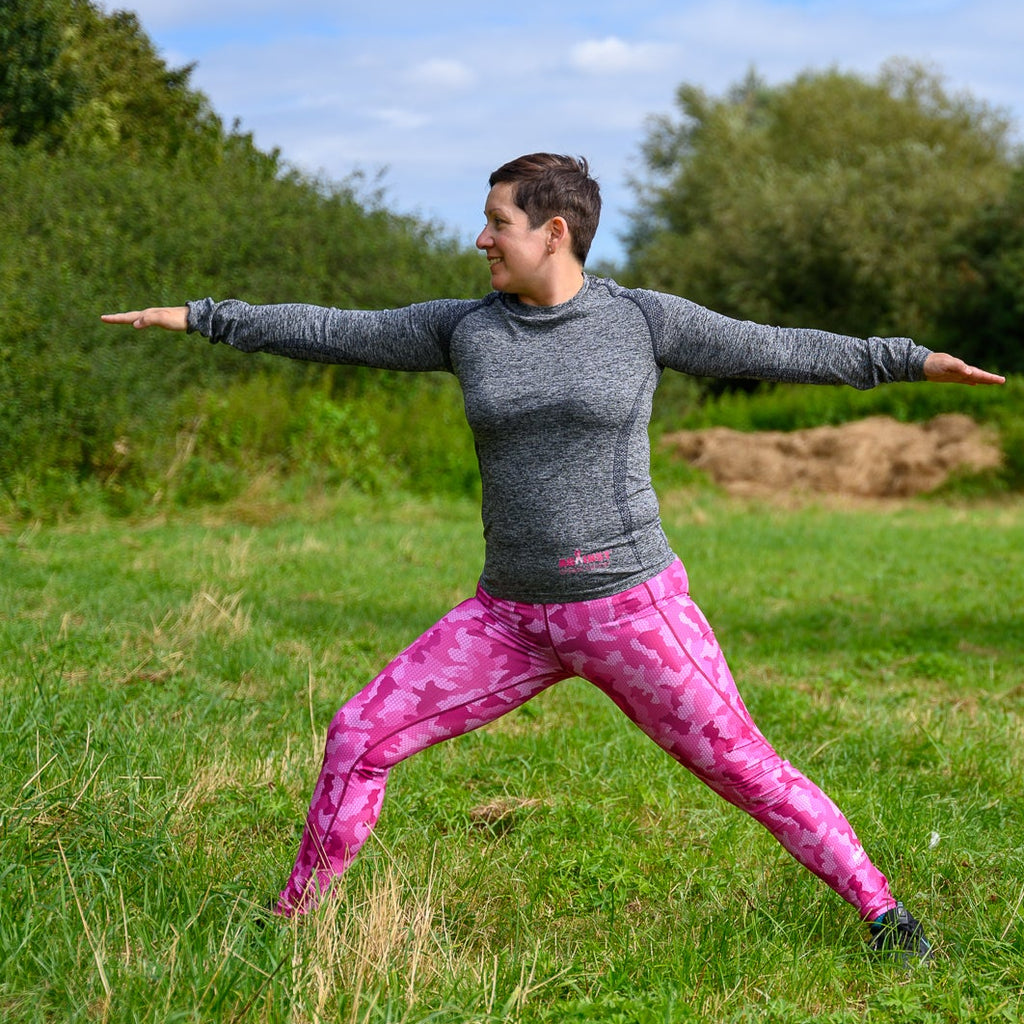Woman practicing yoga in a grassy outdoor setting.