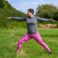 Woman practicing yoga in a grassy outdoor setting.