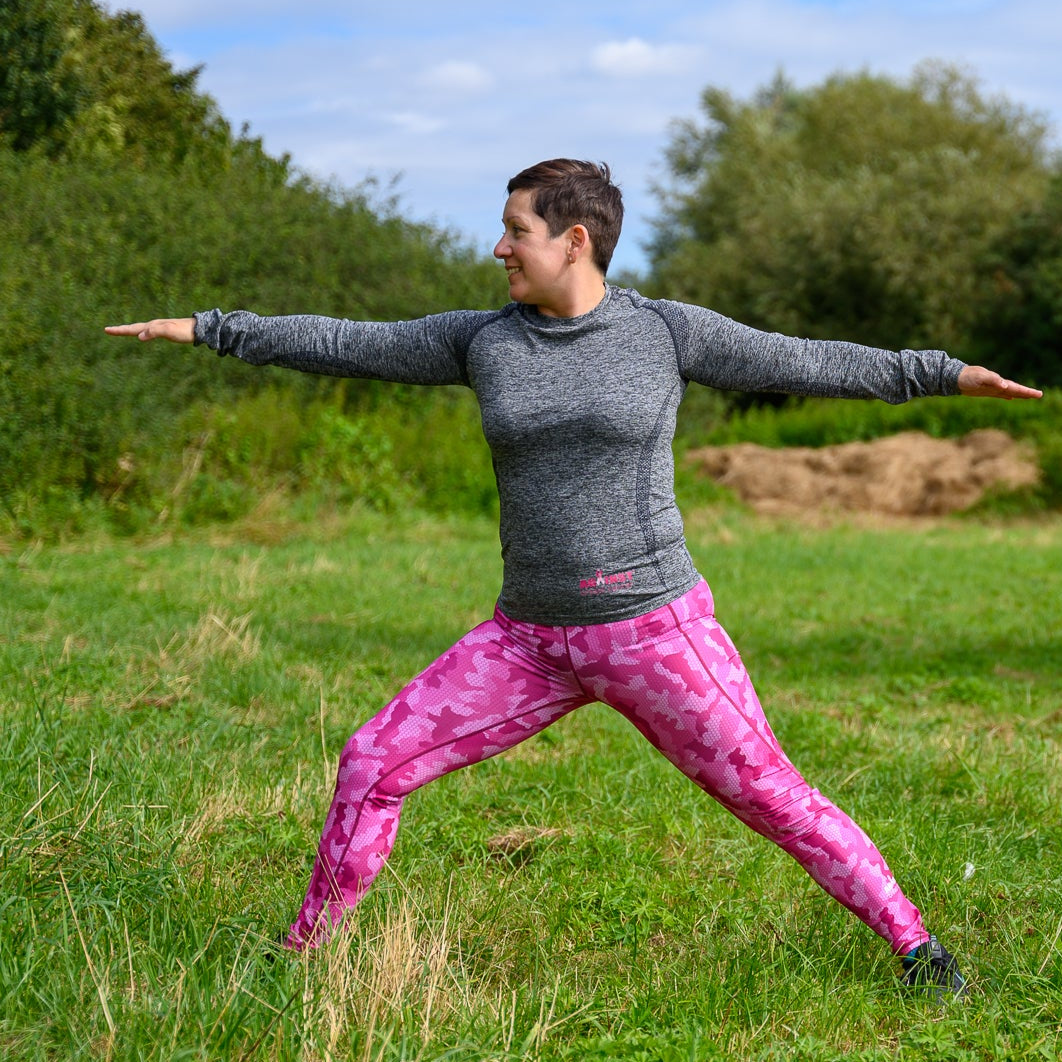 Woman practicing yoga in a grassy outdoor setting.