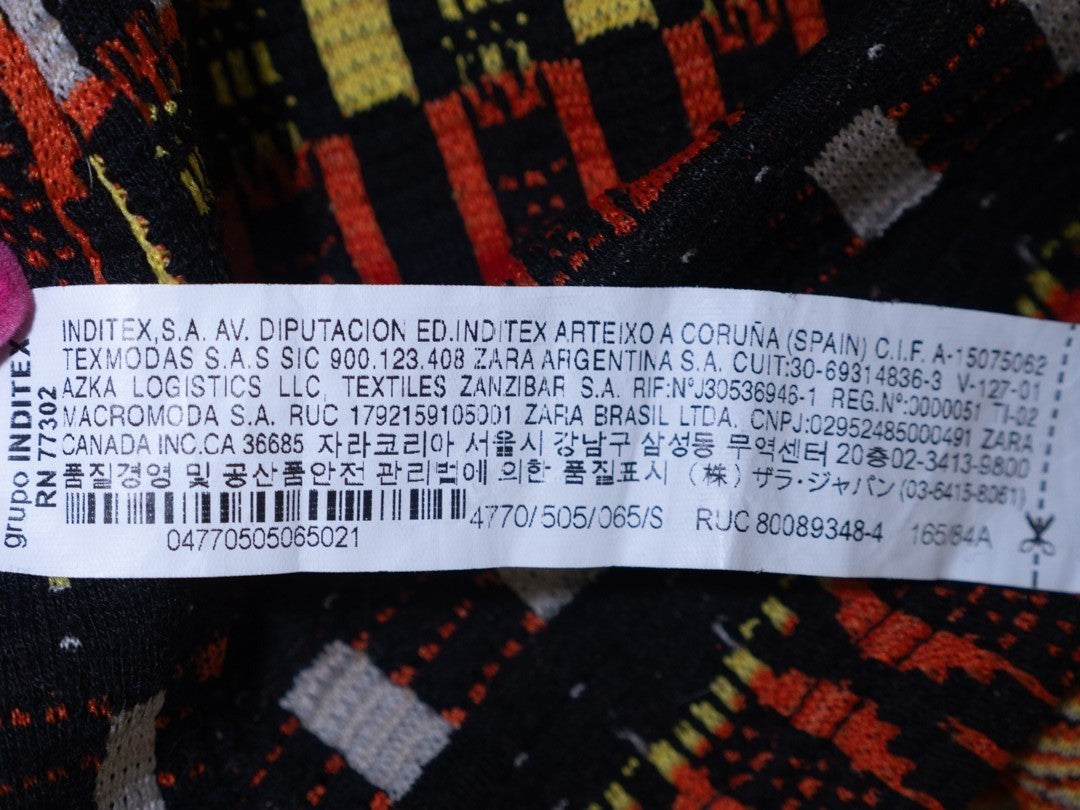 Zara black crewneck sweater with orange, yellow, and cream geometric pattern.