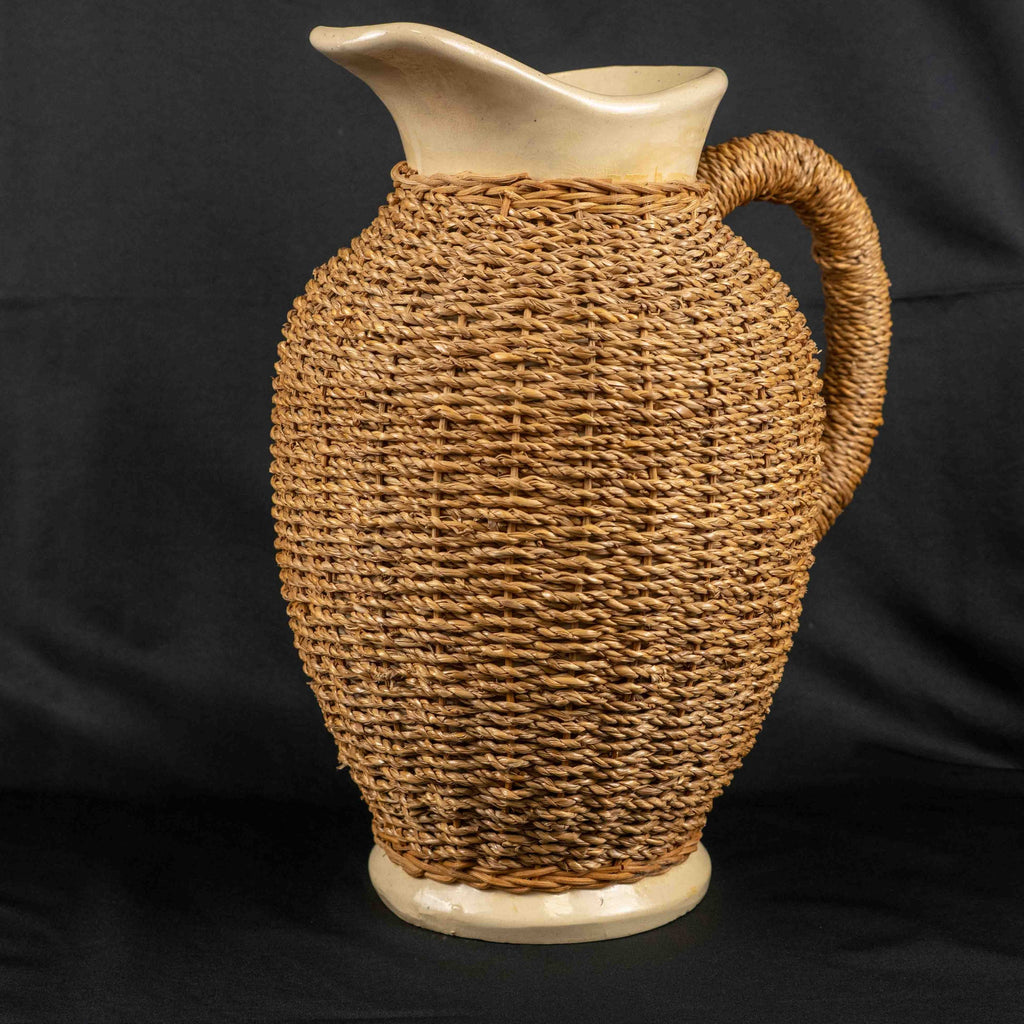Ceramic pitcher jug beige and brown with wicker weave covering and rustic charm.