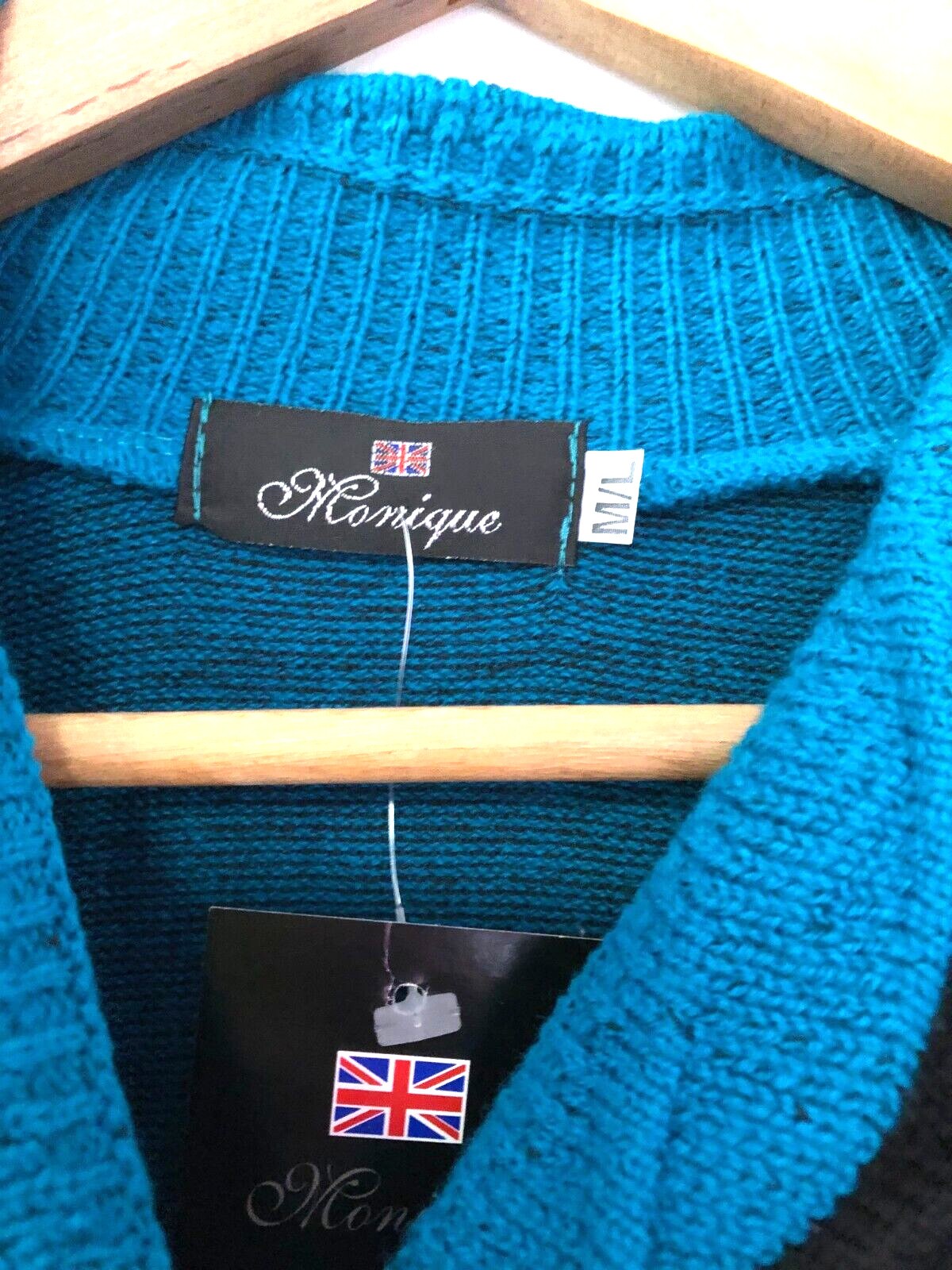 Monique green crewneck sweater with black mock scarf detail and toggle fastening.