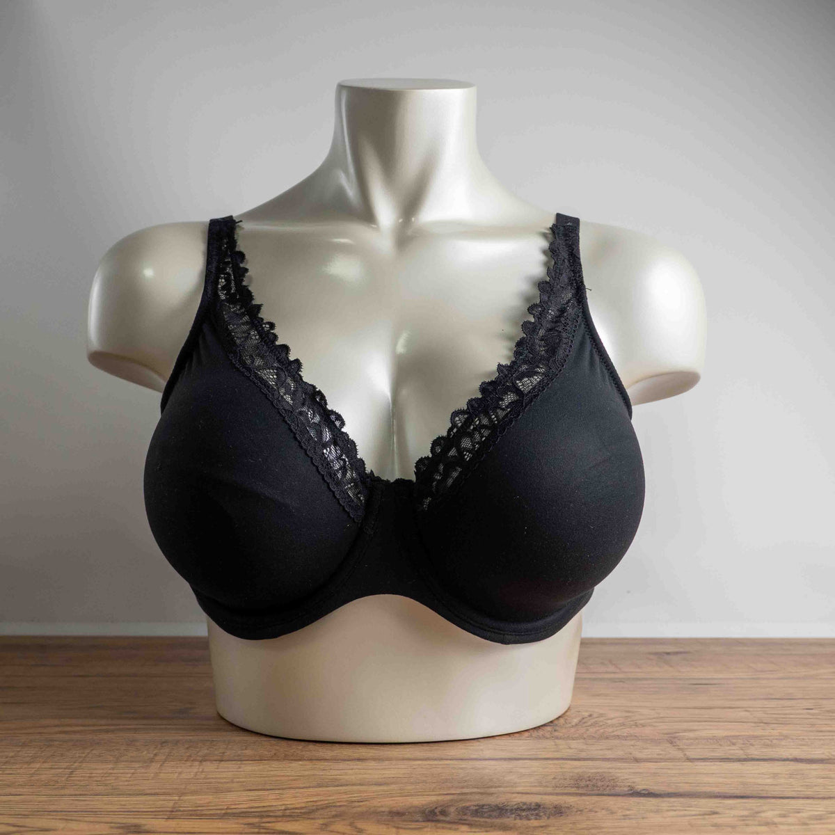 Next black plunge bra with lace trim, adjustable straps, and branded detailing.