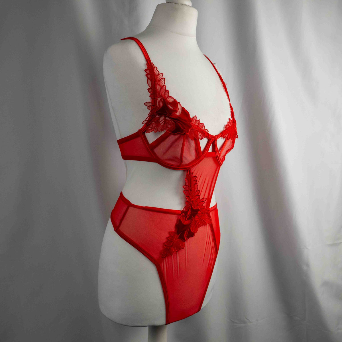Bluebella red lace bodysuit with floral appliques and adjustable straps, underwired design.