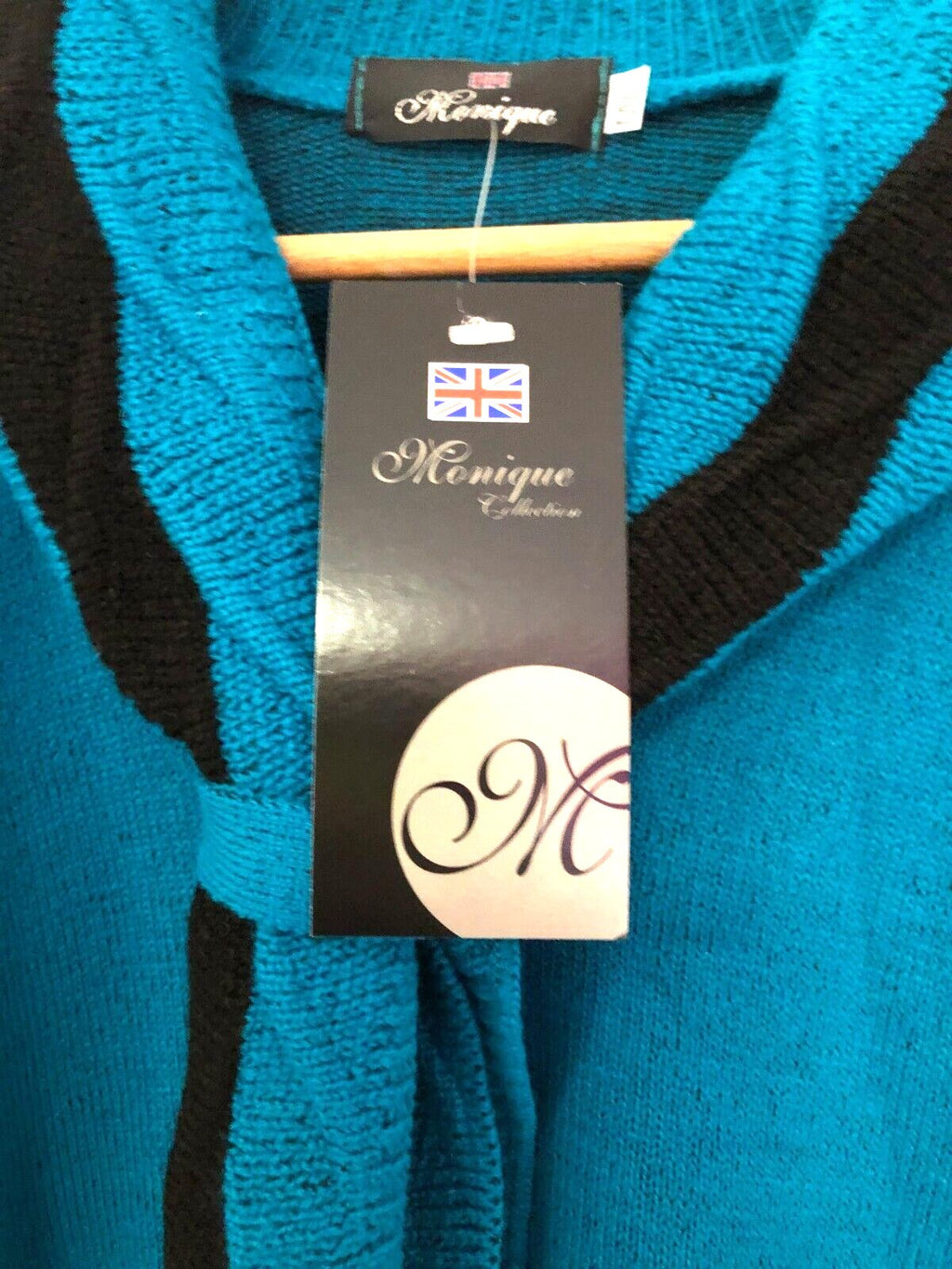 Monique green crewneck sweater with black mock scarf detail and toggle fastening.