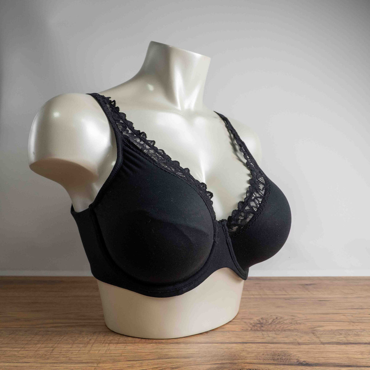 Next black plunge bra with lace trim, adjustable straps, and branded detailing.