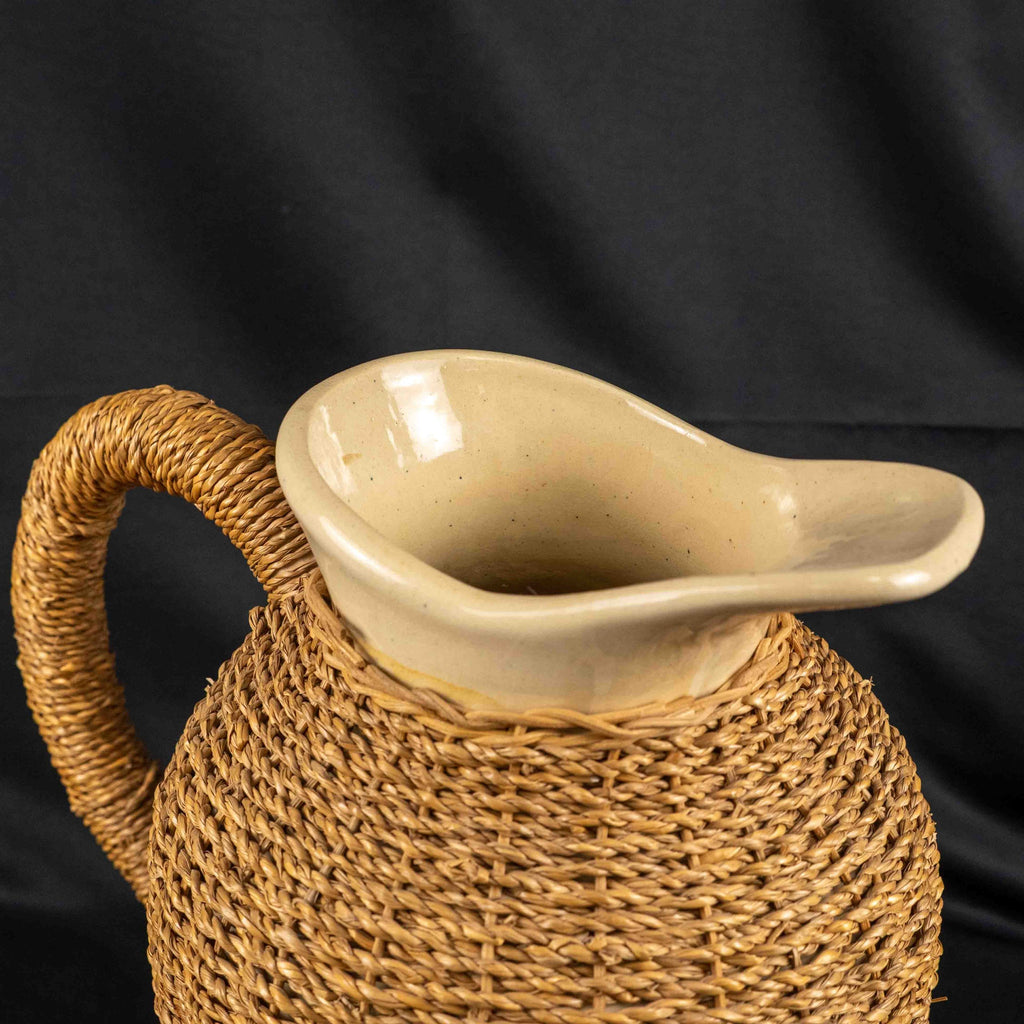 Ceramic pitcher jug beige and brown with wicker weave covering and rustic charm.