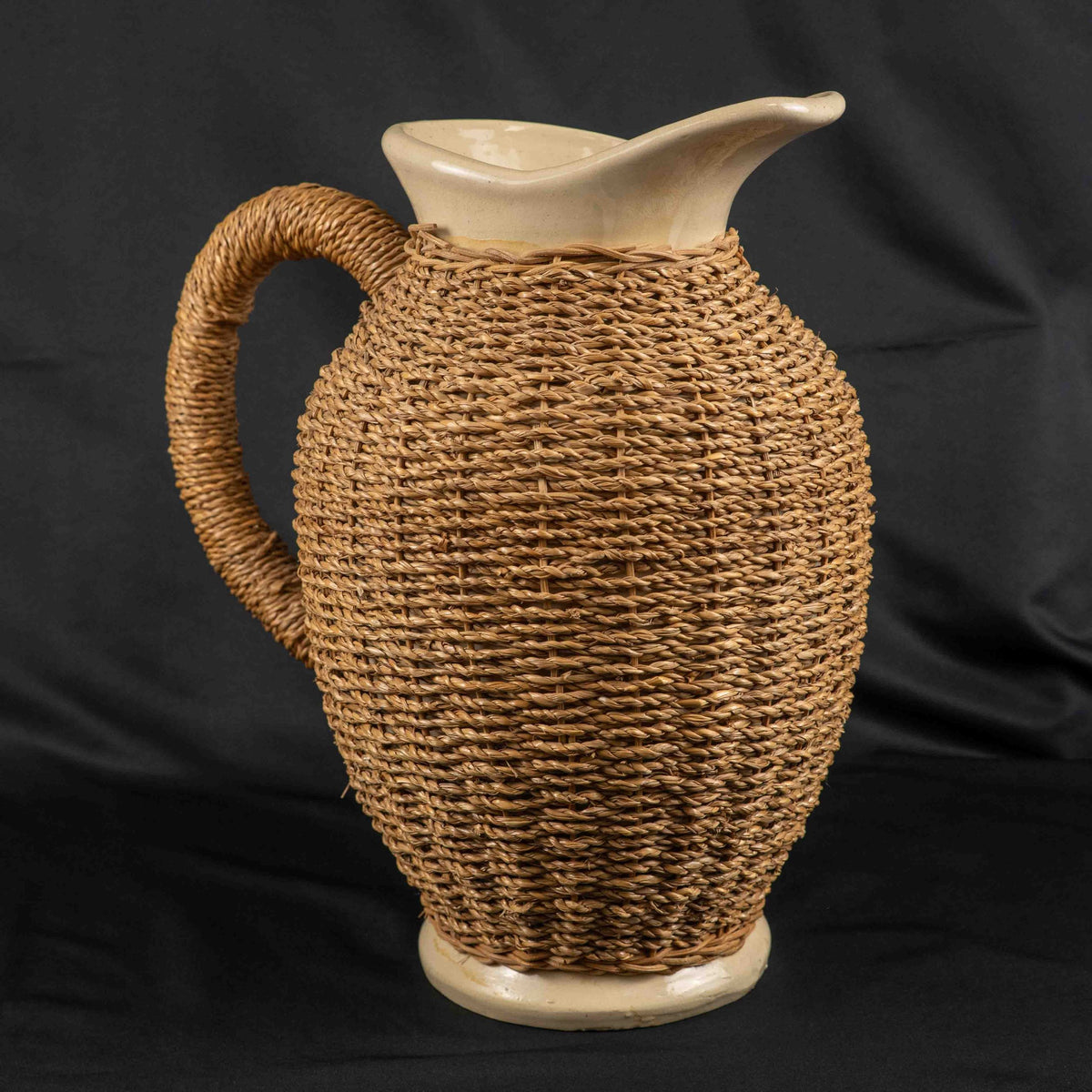 Ceramic pitcher jug beige and brown with wicker weave covering and rustic charm.