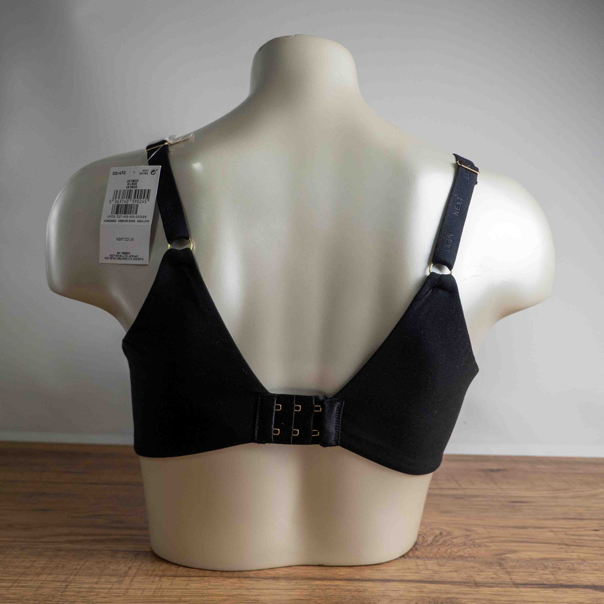 Next black plunge bra with lace trim, adjustable straps, and branded detailing.