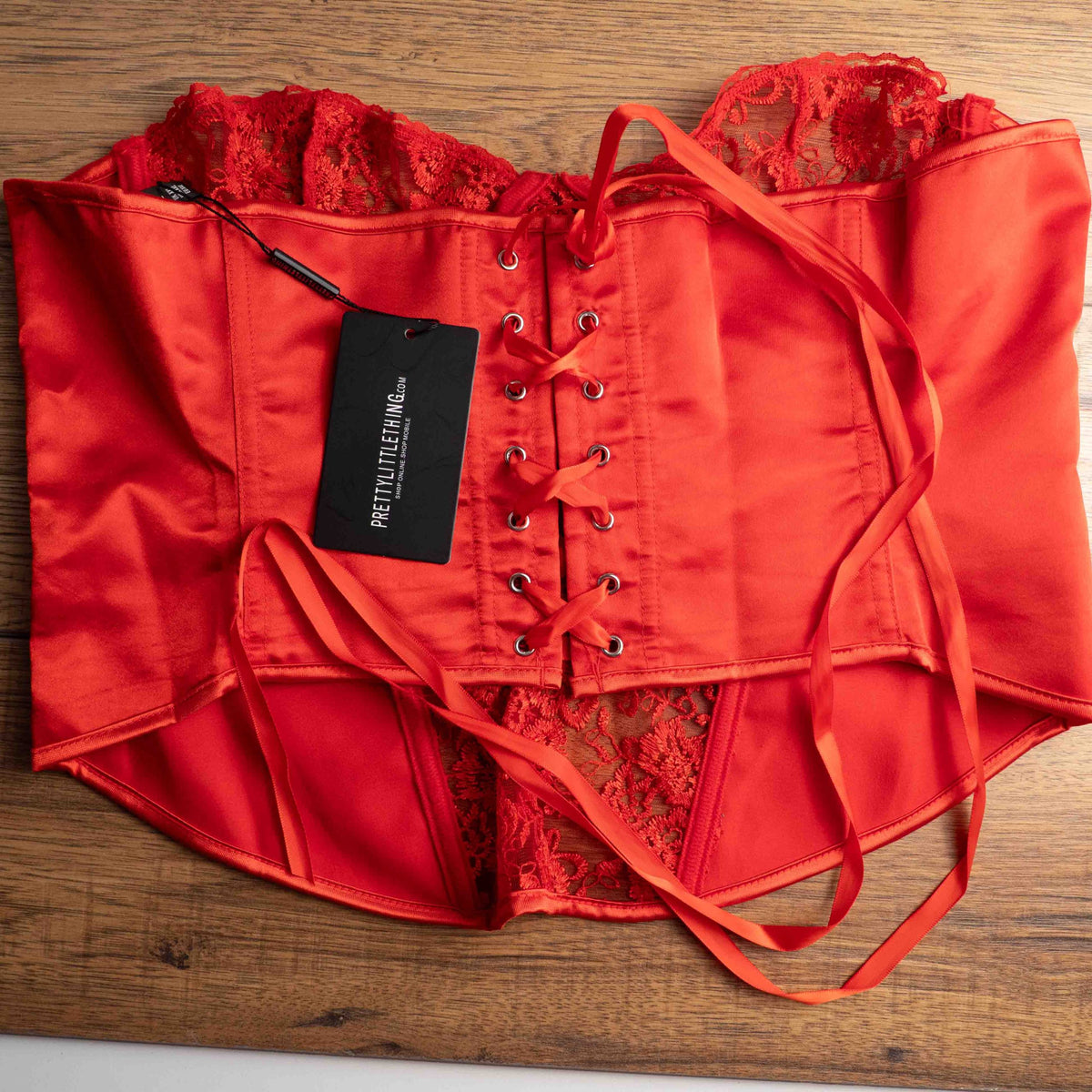 Red corset top with sheer floral lace bodice and satin sides, adjustable lace-up back.
