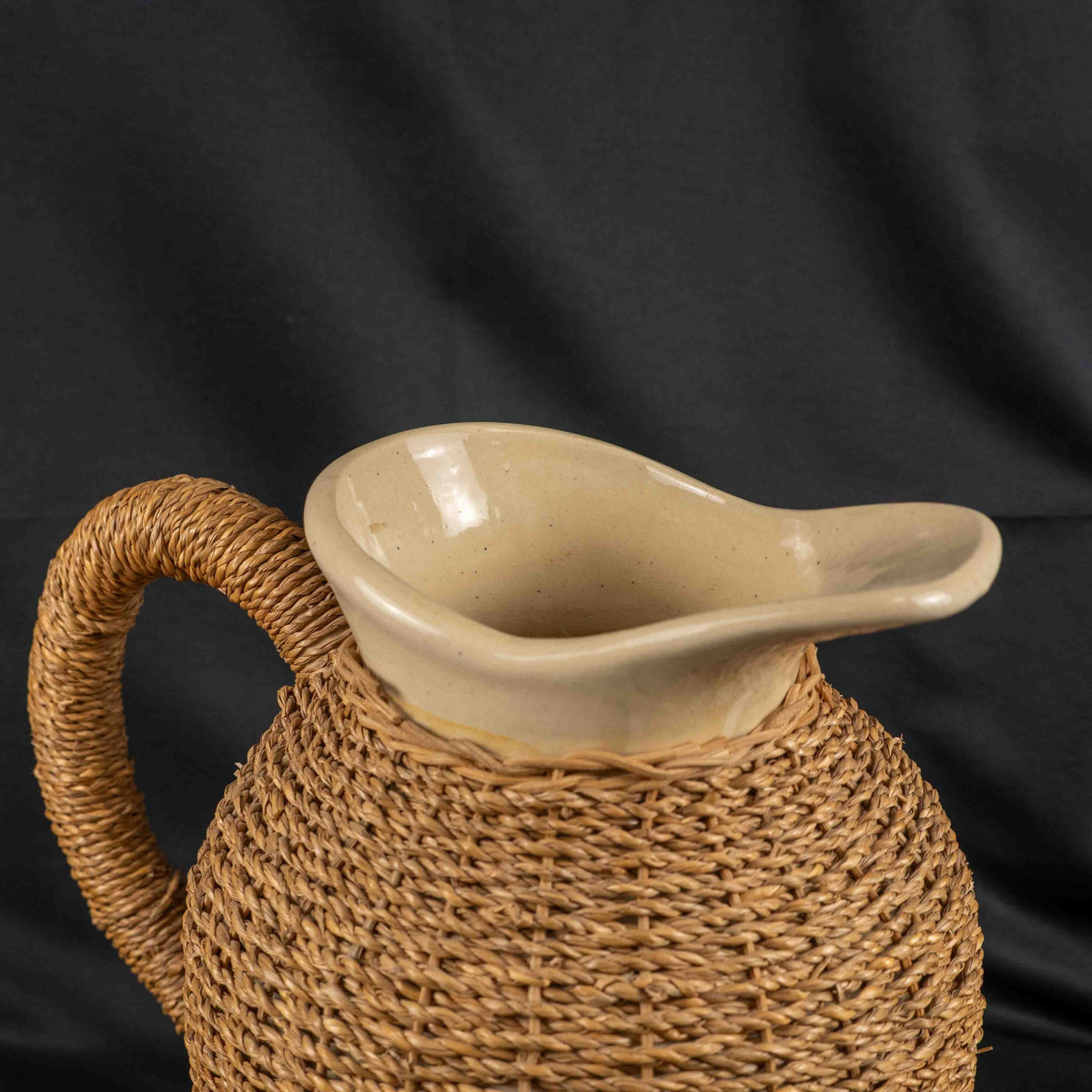 Ceramic pitcher jug beige and brown with wicker weave covering and rustic charm.