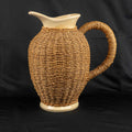Ceramic pitcher jug beige and brown with wicker weave covering and rustic charm.