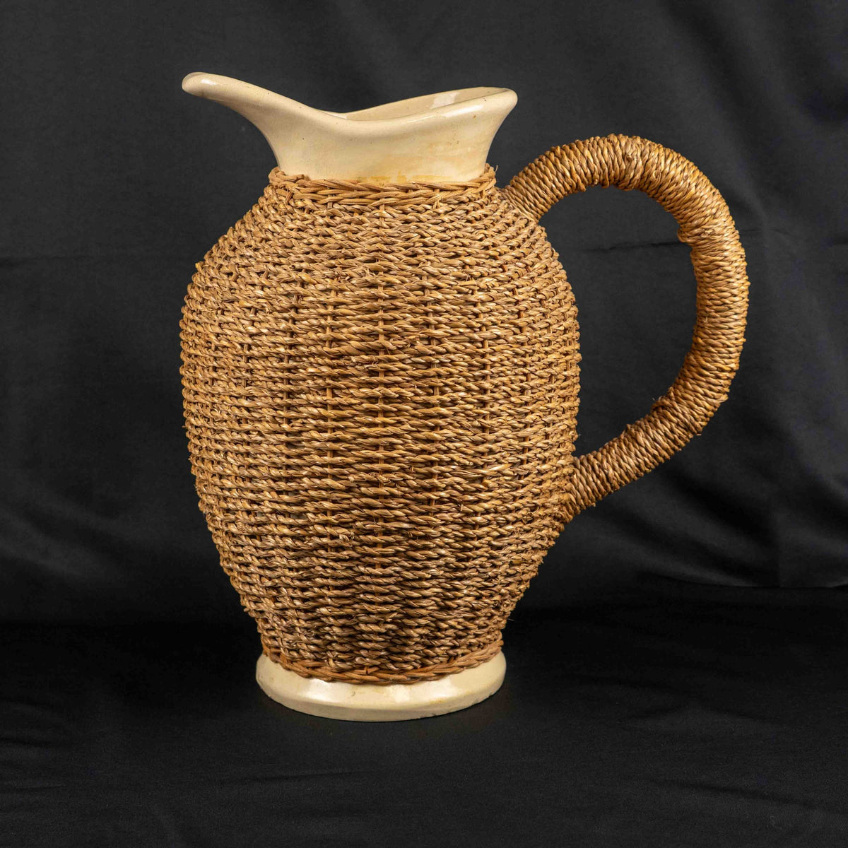 Ceramic pitcher jug beige and brown with wicker weave covering and rustic charm.